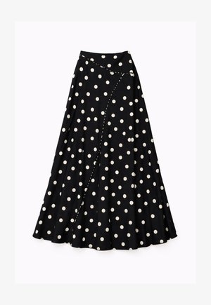 Jupe midi noire à pois blancs avec un design asymétrique portefeuille et des détails de couture incurvée.