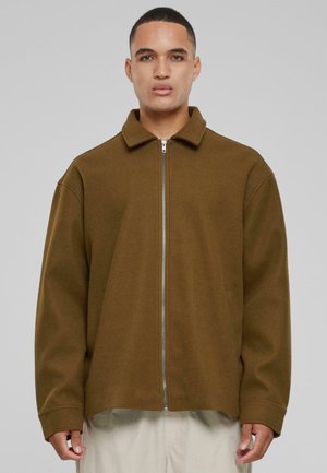 Brun zip-up jacka med krage, tillverkad av ett mjukt material. Har en avslappnad passform och sjunkna axlar. Enkel design, utan mönster.