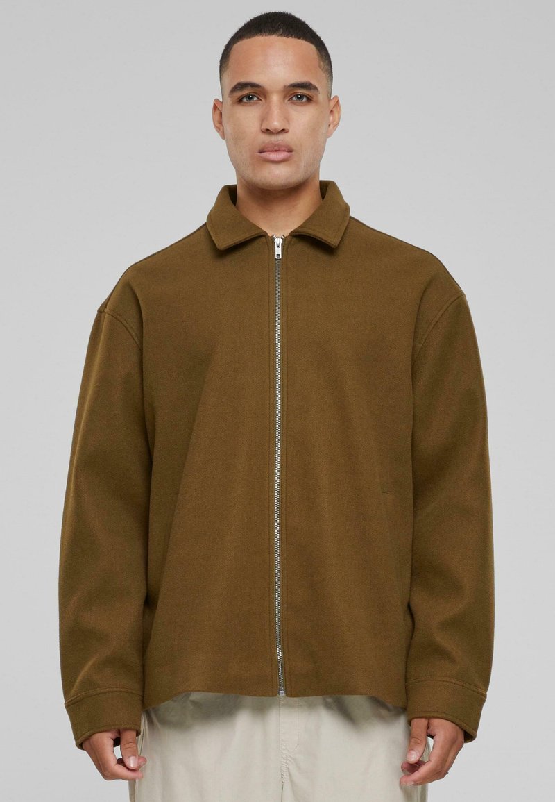 Brown zip-up jacket with a collar, crafted from a soft material. Features a relaxed fit and dropped shoulders. Plain design, no patterns.