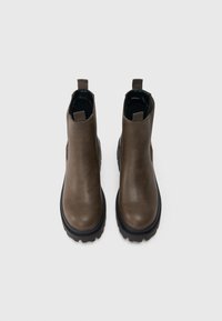 Καφέ δερμάτινες μπότες μέχρι τον αστράγαλο με στρογγυλές μύτες, ελαστικές πλευρικές επενδύσεις και λαβές στο πίσω μέρος; παχιές μαύρες καουτσούκ σόλες με υφή.