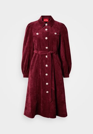 Burgundia sametkleit, millel on krae, pikad puff-sleeved varrukad ja ees olevad taskud. Dekoratiivsed nööbid ja sobiv vöö.