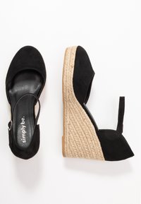 Schwarze Wildleder-Slingback-Wedge-Sandalen mit einem mit Jute umwickelten Absatz und Gummisohle, mit einer runden Zehenpartie und Detail am Knöchelriemen.