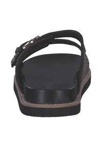 Svarta slip-in sandaler med texturerad övre rem, guldhardware detaljer och en vadderad svart sula; platt design som är lämplig för avslappnad användning.