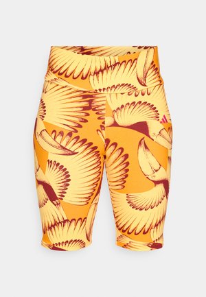 Shorts multicolores avec une base jaune éclatante présentant un motif d'oiseaux rouges et marron avec des détails d'ailes complexes, fabriqués en tissu extensible.