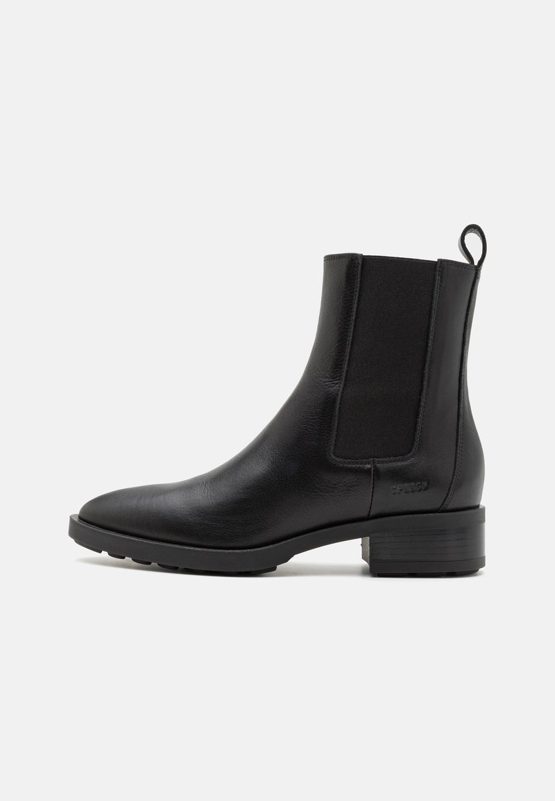 Černá kožená kotníčková bota s elastickými bočními panely, špičatou špičkou a nízkým blokovým podpatkem. Obsahuje zadní poutko pro snadné obouvání.