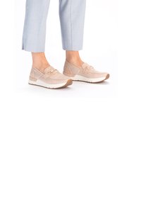 Beige slip-on sneakers with a textured mesh upper, suede accents, and a decorative gold chain detail. White rubber sole and flexible design.