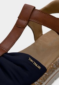 Καφέ σανδάλι με λουρί από συνθετικό δέρμα, με μπλε υφασμάτινη περιοχή στα δάχτυλα, υφή από φελλό στη σόλα με λευκή επένδυση και χρυσή σήμανση "TOM TAILOR".