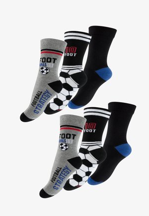Quattro paia di calzini: grigio con grafica di football, nero con accenti rossi, a righe bianche e nere, nero tinta unita con tallone blu.