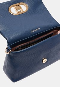 Borsa a mano in pelle blu con texture, dotata di hardware in tono oro, con una chiusura ovale e una tasca interna, che presenta un rivestimento rosa.