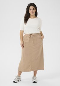 Faldă maxi din bumbac bej, cu un brâu elastic și șnur, având buzunare laterale și tăietură dreaptă. Asortată cu un top alb și adidași.