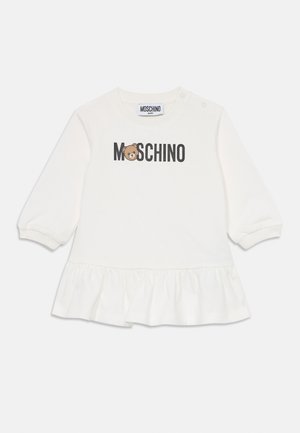 Robe pour bébé à manches longues blanche avec un ourlet à volants, logo MOSCHINO et visage d'ours en peluche sur la poitrine, et boutons-pression à l'épaule.