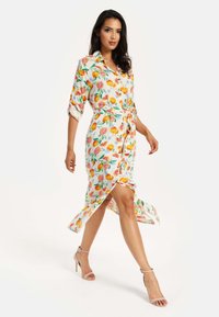 Floral midi dress in lightweight fabric featuring orange and pink fruit patterns, collared neckline, self-tie belt, and side slit.