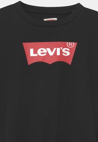 Maglietta nera con scollo rotondo con logo Levi's rosso e bianco al centro del petto.