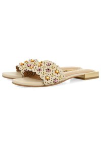 Chanclas beige con un diseño en forma de ondas, que presentan perforaciones y gemas coloridas (rosa, naranja, amarillo) en las correas. Tacón plano.