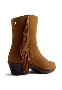 Botín de ante marrón hasta el tobillo con detalle de flecos en el lado, puntera redonda y un tacón bajo apilado. Textura suave con un diseño sencillo.