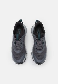 Grijze sportieve schoenen met een ademend mesh bovenwerk, gestructureerde veters en contrasterende teal accenten op de tong en hiel.