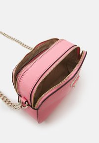 Růžová kabelka s texturovaným povrchem, dvojitými zipovými přihrádkami a stříbrným řetízkem. Interiér je podšitý béžovou tkaninou.