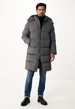 Grijze pufferjas met capuchon, voorzien van horizontaal gestikte secties, een rits aan de voorkant en zijzakken, gedragen over blauwe jeans en zwarte laarzen.