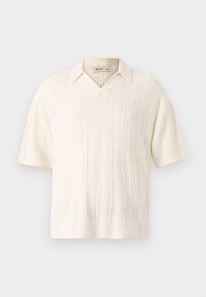 Short-sleeve, cream-colored knit polo shirt with a v-neck design, featuring vertical ribbing texture and a classic collar detail.