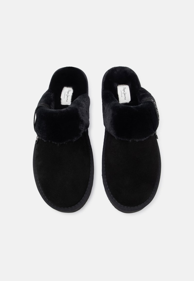 Chaussons noirs à enfiler en daim doux avec une doublure en fourrure moelleuse, présentant un revers replié et une semelle en caoutchouc texturée.