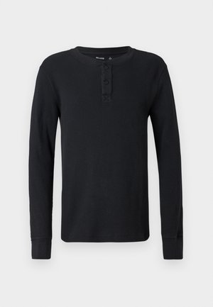 Camisa henley de manga longa preta, feita de malha de waffle texturizada. Apresenta um fechamento com botões e punhos ajustados. Decote redondo simples.