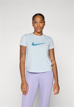Világoskék Nike rövid ujjú póló, türkiz színű swoosh logóval. Formába simuló levendula leggings-szel viselve. Sima anyag, laza dizájn.