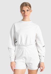 Witte sweatshirt met een ronde halslijn en elastische taille, gecombineerd met bijpassende shorts. Heeft lange mouwen en het merklogo op de mouw.