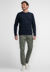 Navy long-sleeve t-shirt, green chinos, and white sneakers, positioned against a plain background, showing a relaxed fit and simple design.