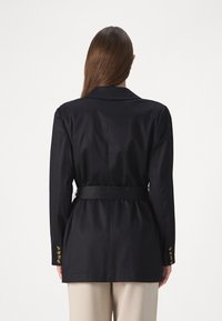 Schwarzer taillierter Blazer mit tailliertem Schnitt, langen Ärmeln und goldenen Knopfakzenten. Glatter Stoff mit strukturiertem Design.