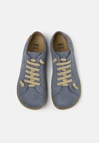 Vaaleansiniset mokkanahkaiset lenkkarit, joissa beiget nauhat, pyöreä muoto, teksturoitu pinta ja kumipohjat. Brändin logo näkyvissä sisäpuolella.