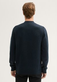 Pull en maille bleu marine avec col rond, manches longues, poignets côtelés et une finition texturée. Design simple et classique sans embellissements.