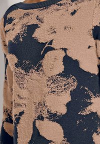 Strickpullover mit dunkelblauem Grund und einer strukturierten beige-blumigen Musterung. Rundhalsausschnitt und lange Ärmel, weicher Stoff.