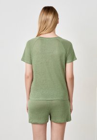 Haut vert à manches courtes et shorts assortis en tissu doux et texturé. Design décontracté avec une coupe ample et un ourlet arrondi.