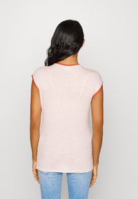 Camiseta às riscas vermelhas e brancas com mangas curtas e decote redondo, apresentando um acabamento sólido em vermelho no colarinho e nas mangas.