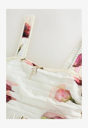 Floral-patterned dress with pale fabric, featuring pink and maroon roses, textured pleats, and decorative pom-pom trim on straps.