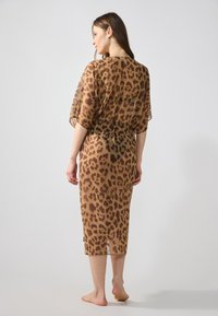 Häntävä ruskea leopardi-kuosiset mekko, keskipitkä, rento malli, lyhyet hihat ja sivuaukot helmassa. Kevyt, laskeutuu pehmeästi.