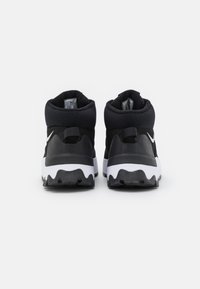 Zwarte high-top sneakers met een gestructureerde zwarte bovenkant, witte tussenzool en gekartelde zool; voorzien van een klein wit logo aan de zijkant.