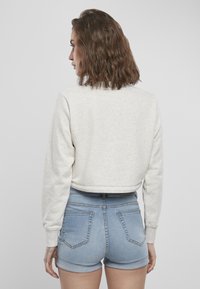 Lyse grå cropped hettegenser med lange ermer, myk tekstur. Kombinert med høy midje denimshorts, med lys vask og rulleflater.