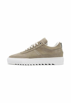 Lage beige suède sneaker met dikke witte gezaagde zool, ronde neus, veters en "DUTCH ID"-branding aan de zijkant.