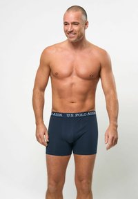 Mørkeblå boxershorts med en U.S. Polo Assn. logo på livet, lavet af et glat, elastisk materiale, tætsiddende design, uden mønstre.