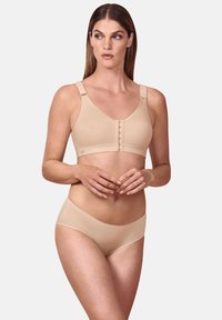 Beige kabelloser BH mit breiten Trägern, Haken- und Ösenverschluss vorne und glattem Stoff. Kombiniert mit passendem nahtlosem Bikiniunterteil.