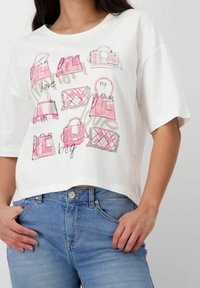 Bílý zkrácený tričko s grafickým designem různých růžových kabelek, s černými obrysy a textem "my love bag."