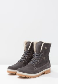 Bottes chevilles en daim gris avec doublure en fausse fourrure, semelle en caoutchouc, œillets en métal et lacets bleus. Caractérisées par un col rembourré et des accents de couture.