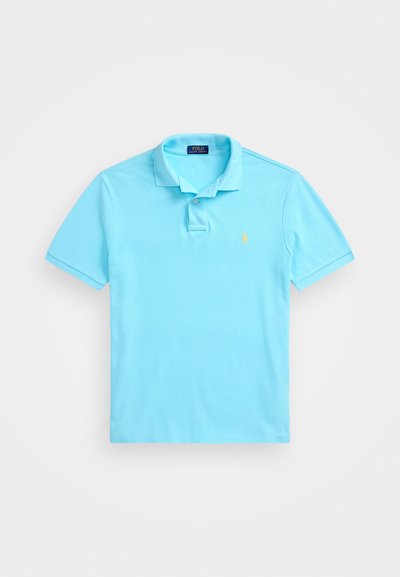 Polo de culoare albastru deschis, realizat din bumbac, cu guler, placket cu două butoane și un logo brodat pe pieptul stâng. Mâneci scurte.