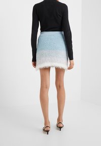 Vävt texturerat minikjol i ljusblått och vitt, med en fransad nederkant och en slät midja. Matchad med en svart långärmad topp.