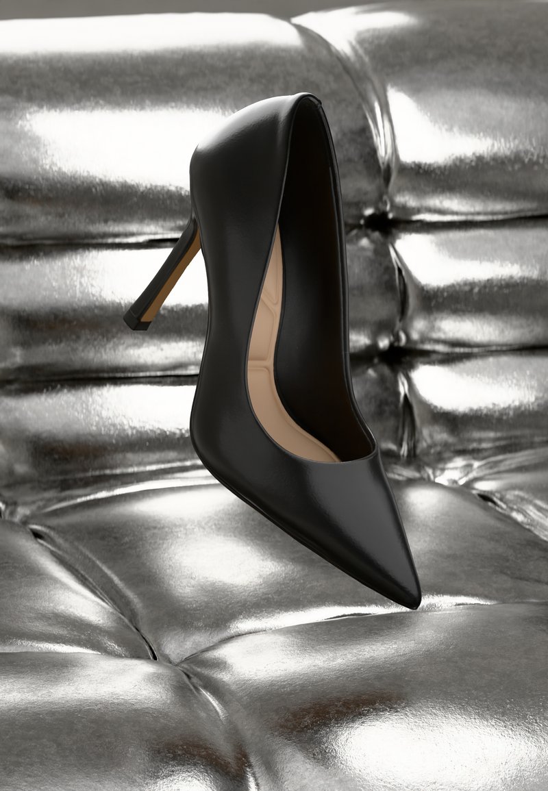 Scarpa nera con tacco alto, punta affusolata, materiale in pelle liscia, design elegante e silhouette strutturata, posizionata su uno sfondo argentato lucido.