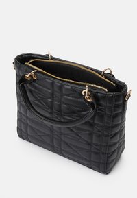 Sac à main noir matelassé en cuir, doté de quincaillerie dorée, de doubles poignées supérieures et d'une fermeture éclair avec un compartiment intérieur.