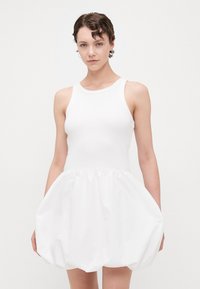 Weißes Kleid mit tailliertem Oberteil und voluminösem Ballonrock. Glattes, elastisches Obermaterial; strukturierter, leichter Unterstoff.
