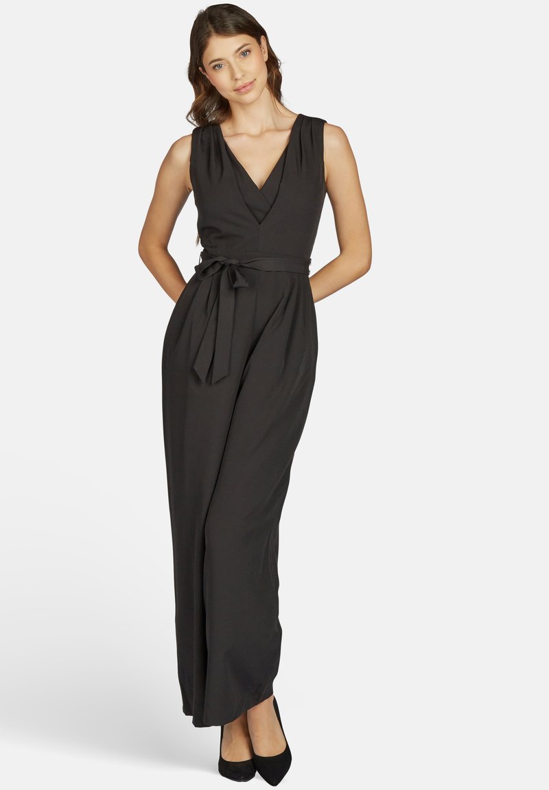 Schwarzer ärmelloser Jumpsuit mit V-Ausschnitt, tailliert mit einem Gurt, weit fließenden Beinen und glatter Stofftextur.
