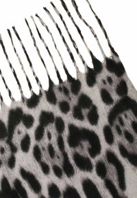 Graues und schwarzes Leopardenmuster-Gewebe mit fransigen, gedrehten Quasten entlang einer Kante.
